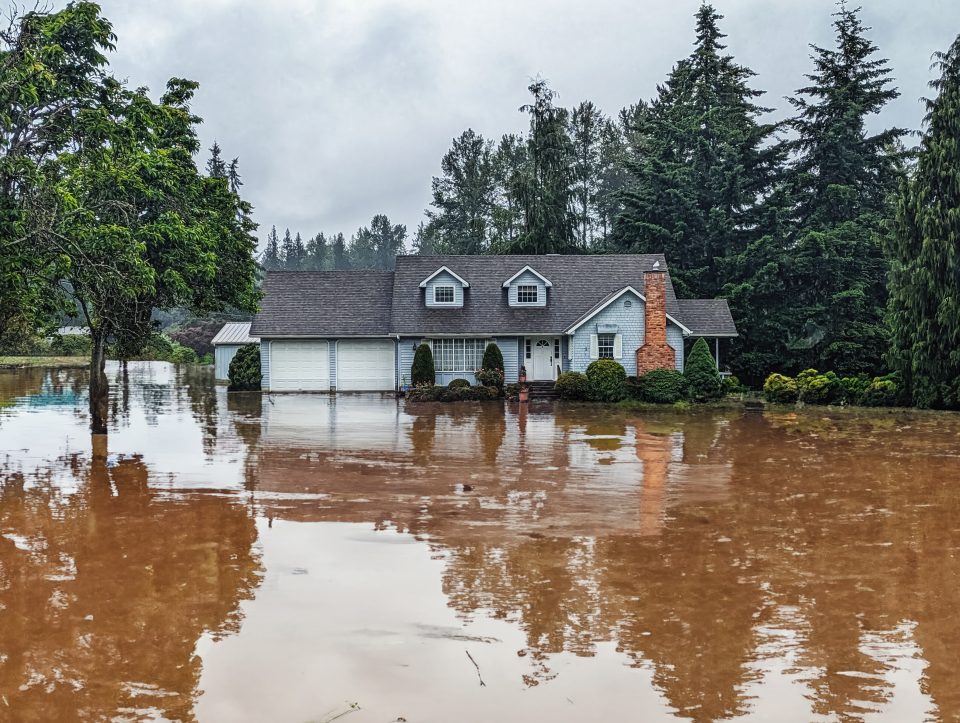 Photo of house exterior with flooded yard; artificially rendered